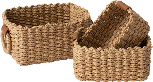 Set of three woven wicker storage baskets with round handles and decorative vegan leather tags.