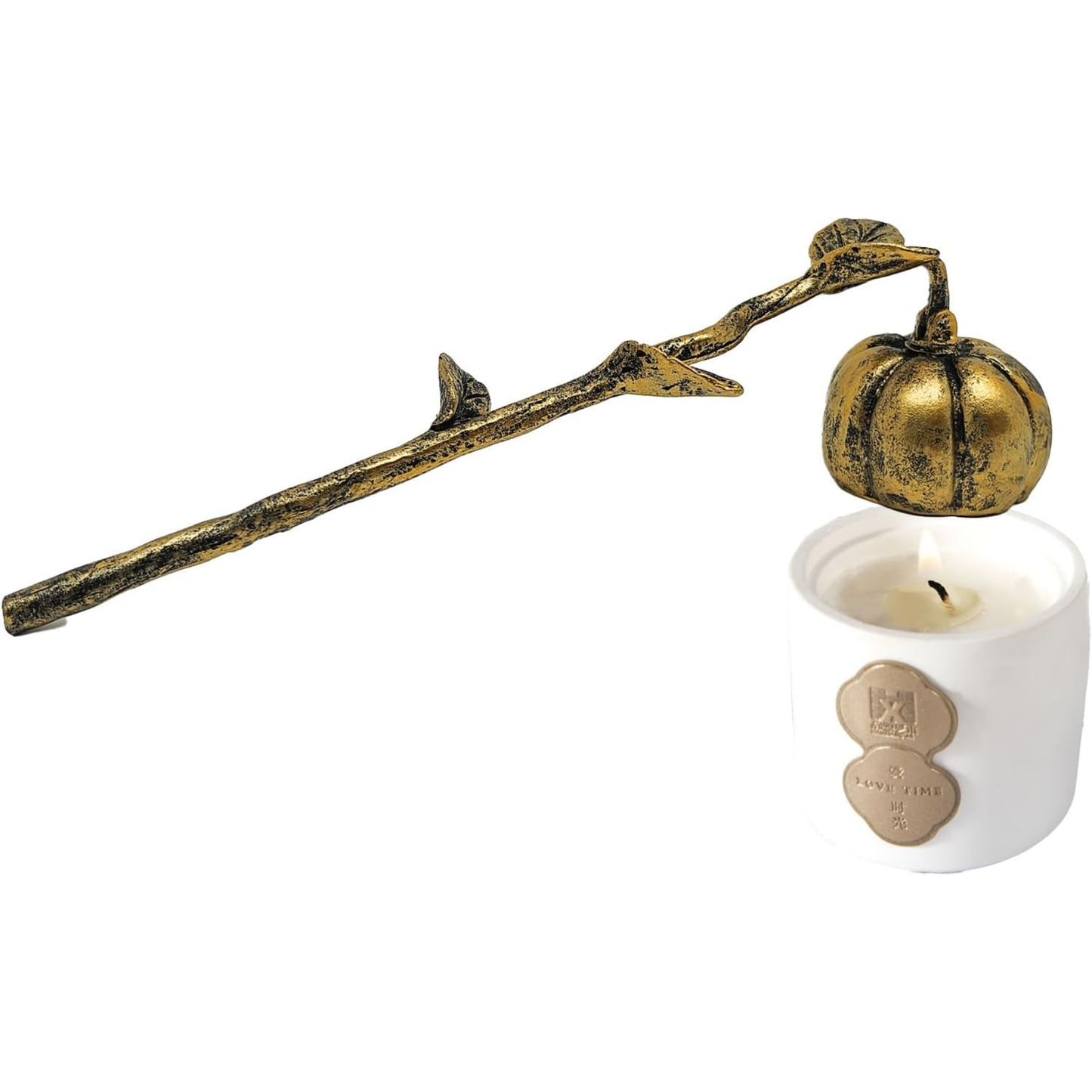 A decorative brass pumpkin candle holder with a branch and leaf design, shown holding a lit white candle in a white holder against a white background.