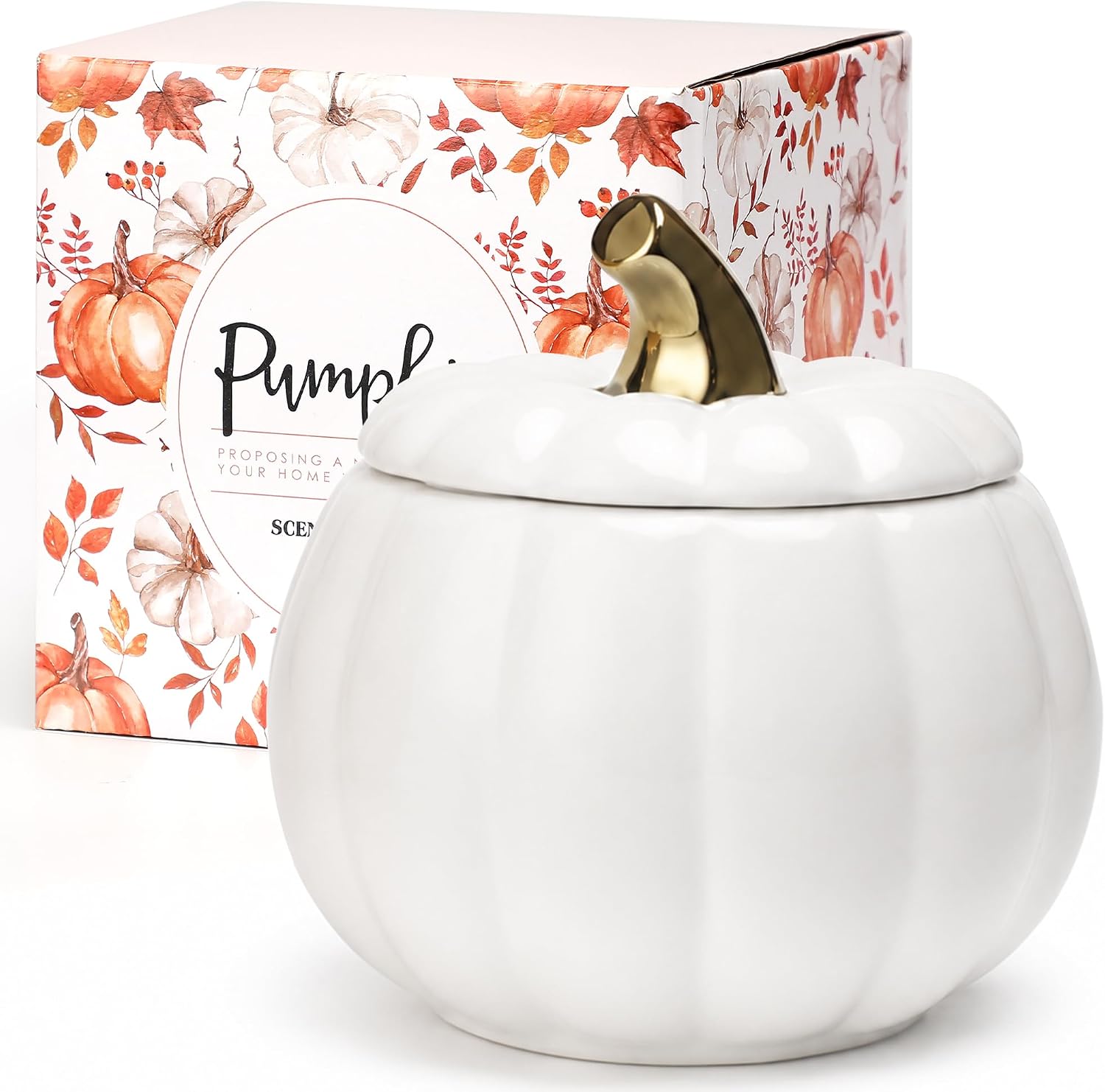 A white ceramic pumpkin-shaped scented candle jar with a lid and a metallic gold stem, shown in front of its illustrated retail box featuring pumpkins and autumn leaves.