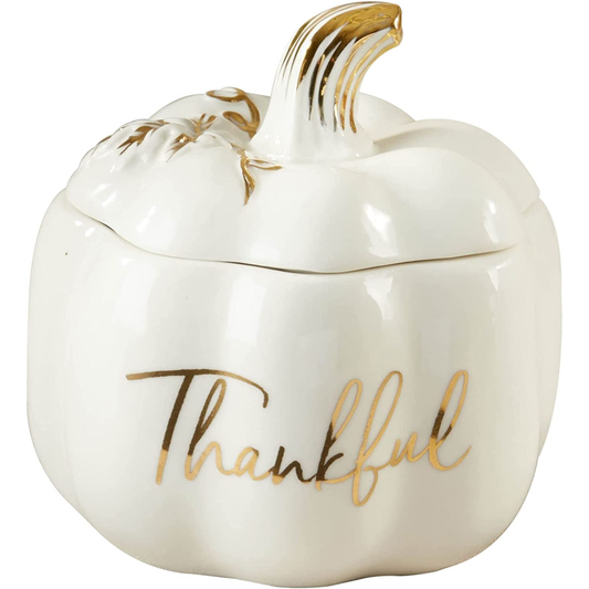 A white ceramic pumpkin-shaped container with a lid, featuring gold-leaf accents on the stem and the word 'Thankful' in cursive script on the front, set against a plain white background.